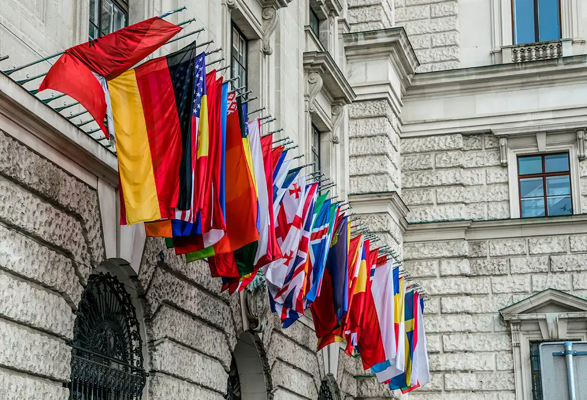 Fila di bandiere nazionali sulla facciata di un edificio diplomatico, simbolo delle rappresentanze internazionali che un ministero degli Esteri mantiene in tutto il mondo.